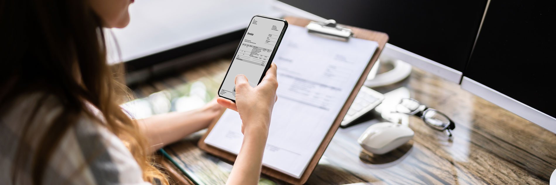 Person using smartphone to scan a document on a clipboard.